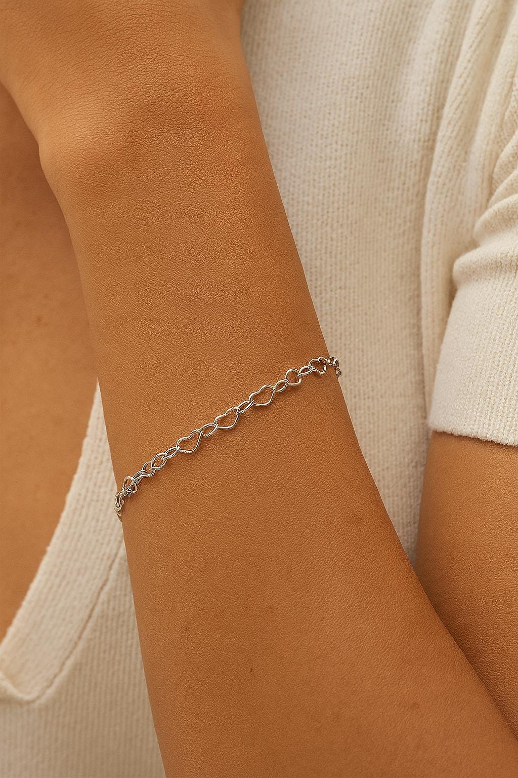 Close-up of a person's arm wearing a silver chain bracelet.