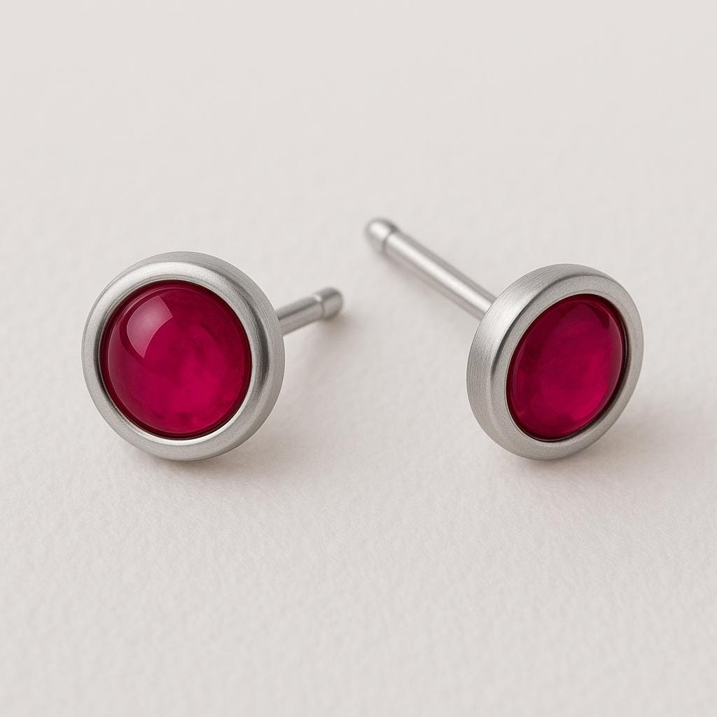 Silver earrings with red gemstones on a light gray background