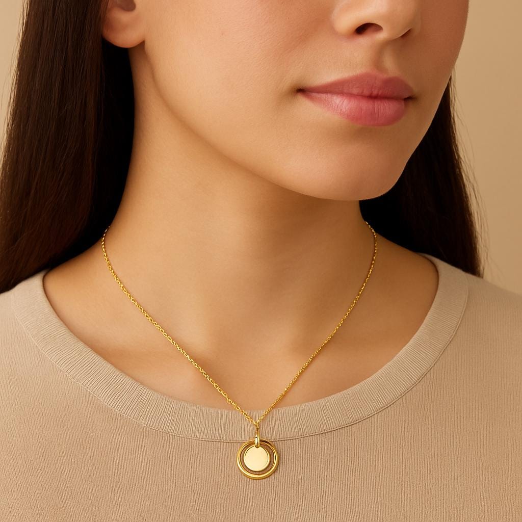 Close-up of a woman wearing a gold necklace with a round pendant against a beige background