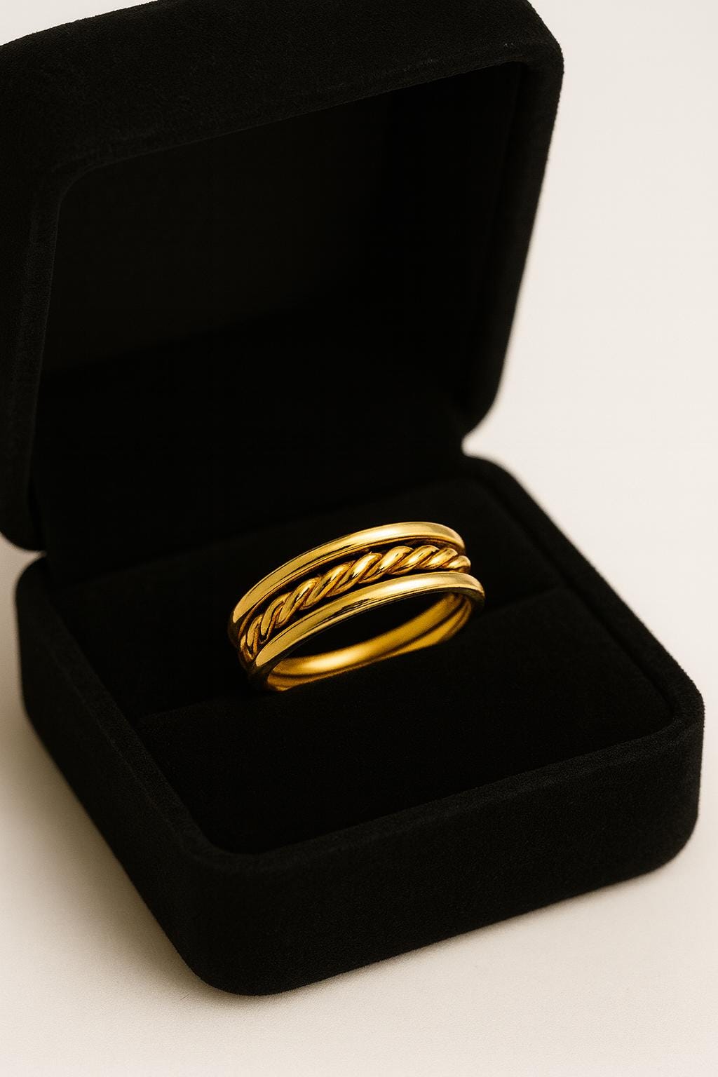 Gold ring in a black velvet box on a light background