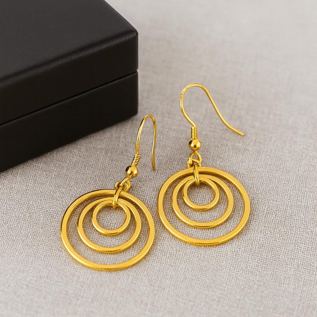 Gold Brass Dangle earrings on a textured surface with a black box in the background