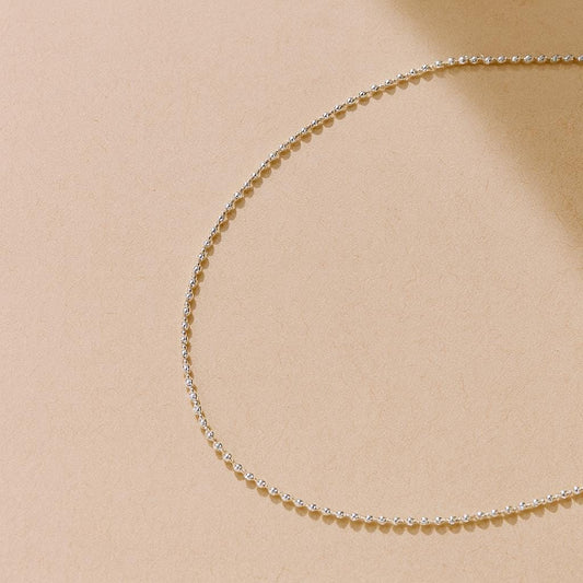 Delicate silver chain necklace on a beige background