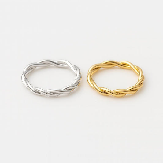 Two twisted rings, one silver and one gold, on a white background