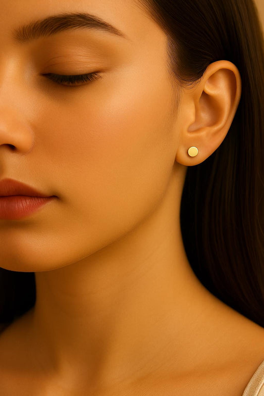 Close-up of a woman wearing a gold earring with a warm, yellowish light.
