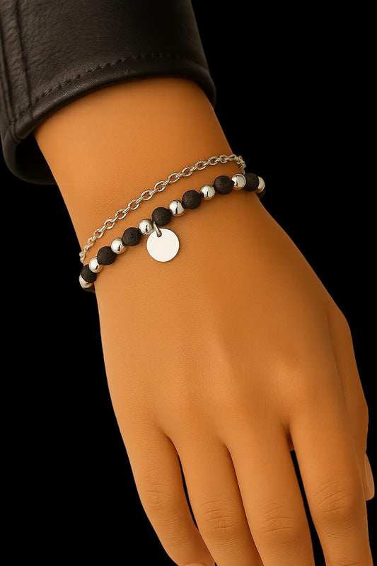 Hand wearing a bracelet with black beads and silver accents on a black background