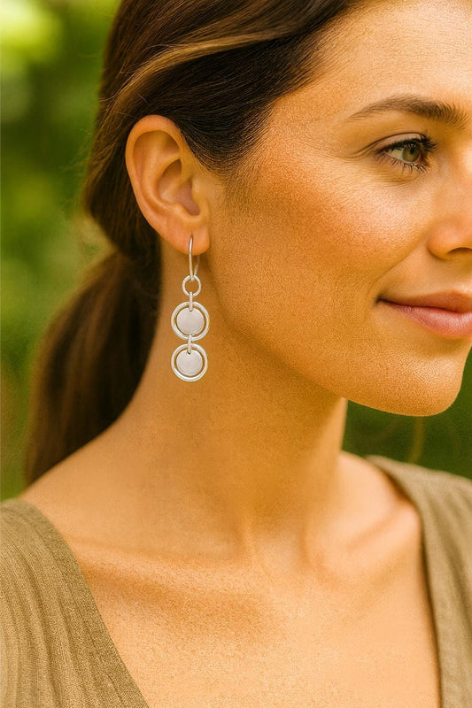 Close-up of a woman wearing silver earrings with a blurred green background