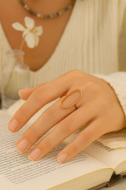 Hand wearing a gold ring on an open book with a blurred background