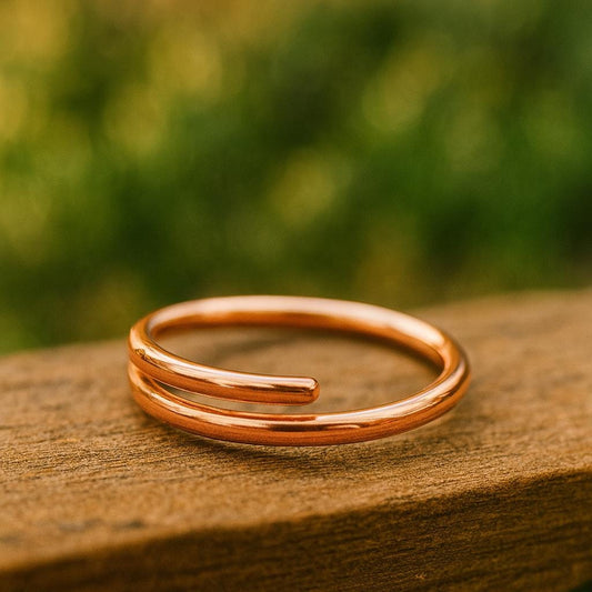 Rose gold ring on a wooden surface with a blurred green background