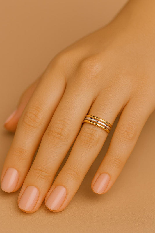 Gold ring on a hand with a beige background