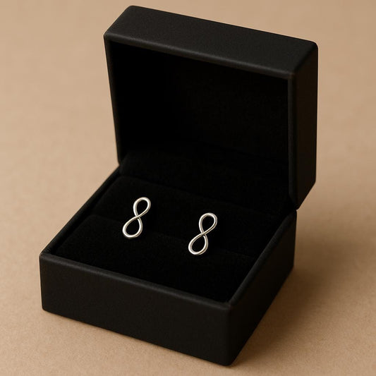 Silver infinity symbol earrings in a black jewelry box on a beige background