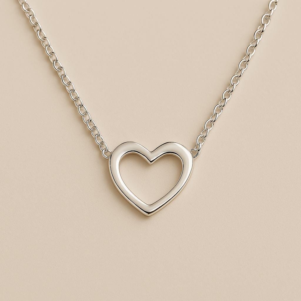 Silver heart-shaped necklace on a beige background