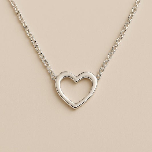 Silver heart-shaped necklace on a beige background