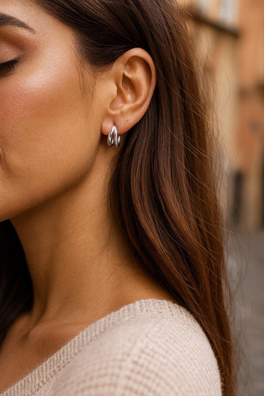 Close-up of a woman wearing silver hoop earrings with a blurred background
