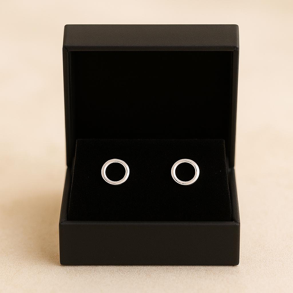 Silver circular earrings in a black jewelry box on a beige background