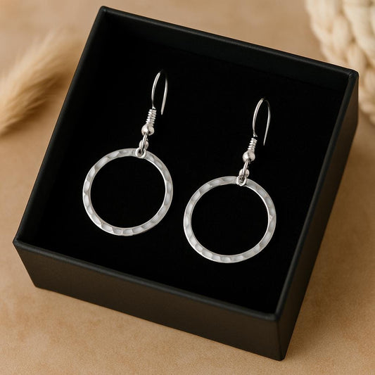 Silver hoop earrings in a black box on a beige background
