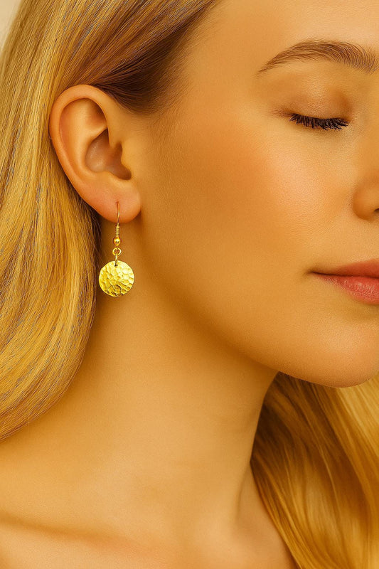 Close-up of a woman wearing gold earrings with a soft focus on her face and hair.