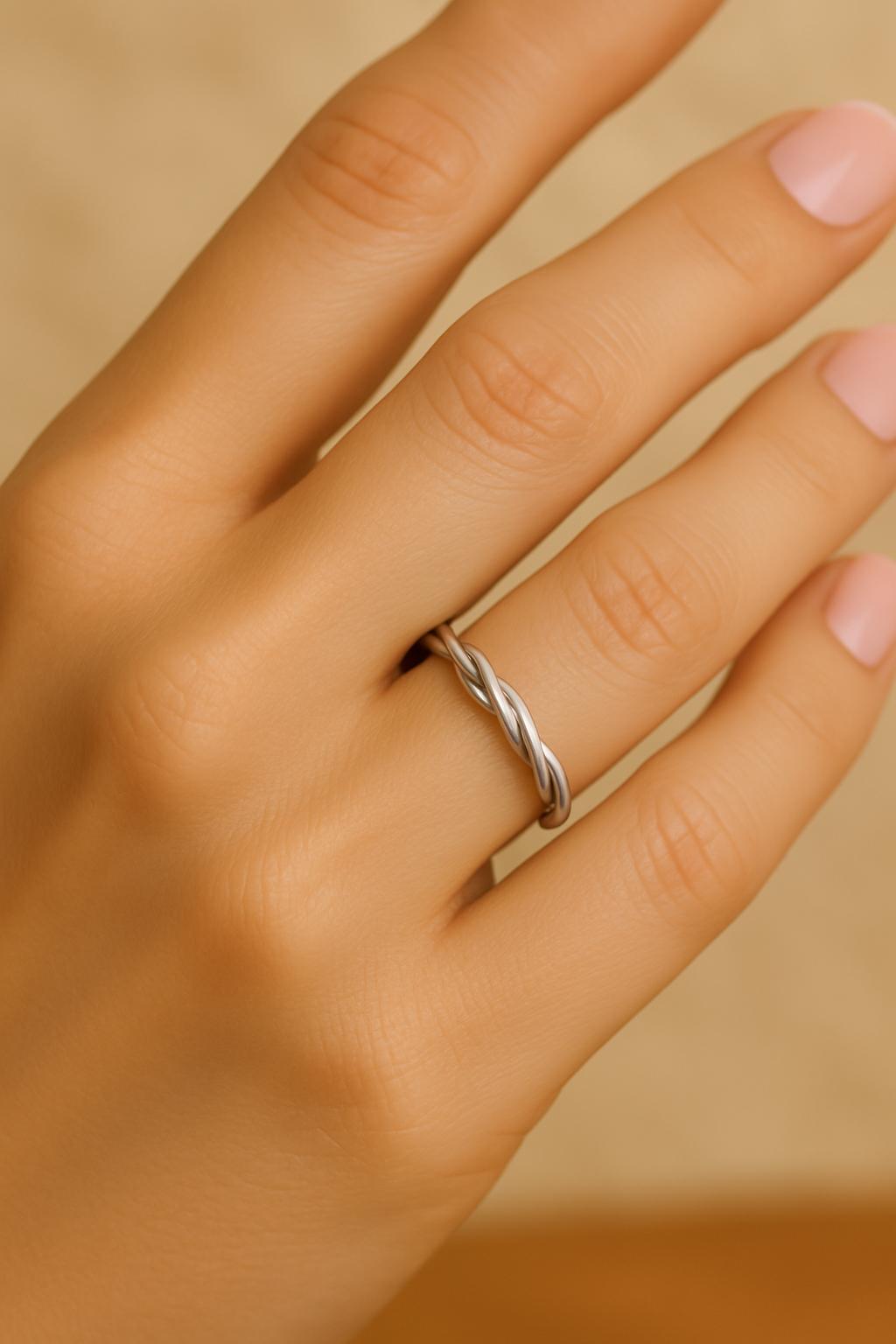 Silver ring on a person's finger against a beige background