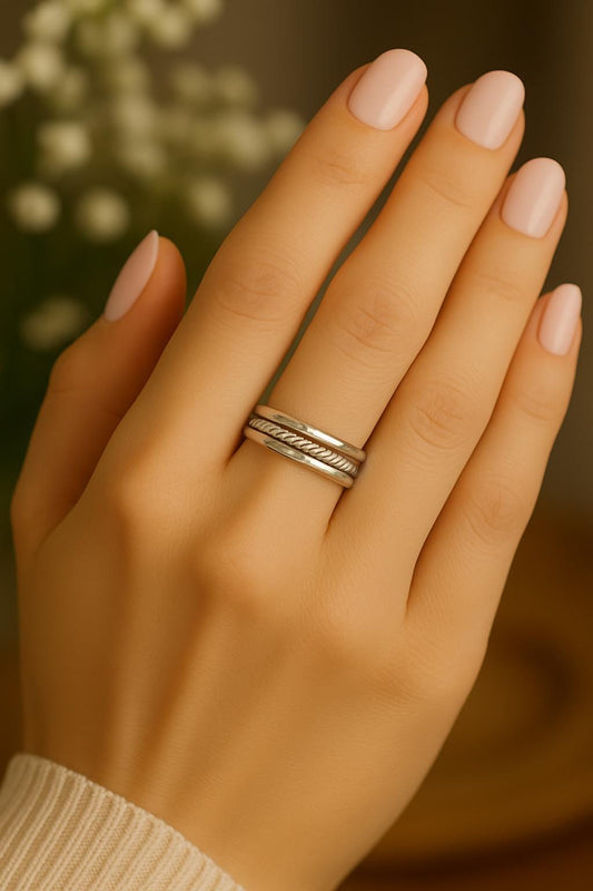 Hand wearing a silver ring with a blurred background