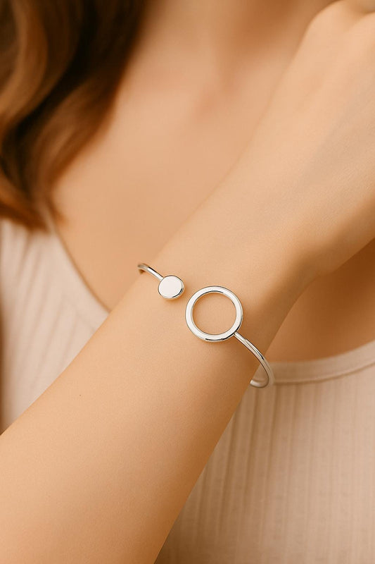 Silver bracelet on a wrist with a neutral background