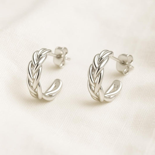 Pair of silver hoop earrings on a light beige background