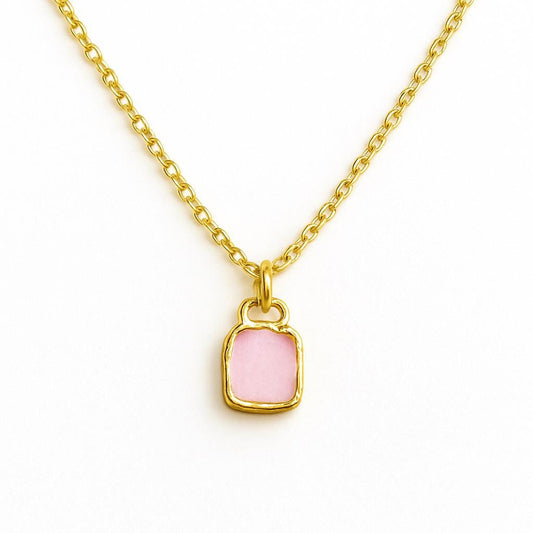 Gold necklace with a pink pendant on a white background