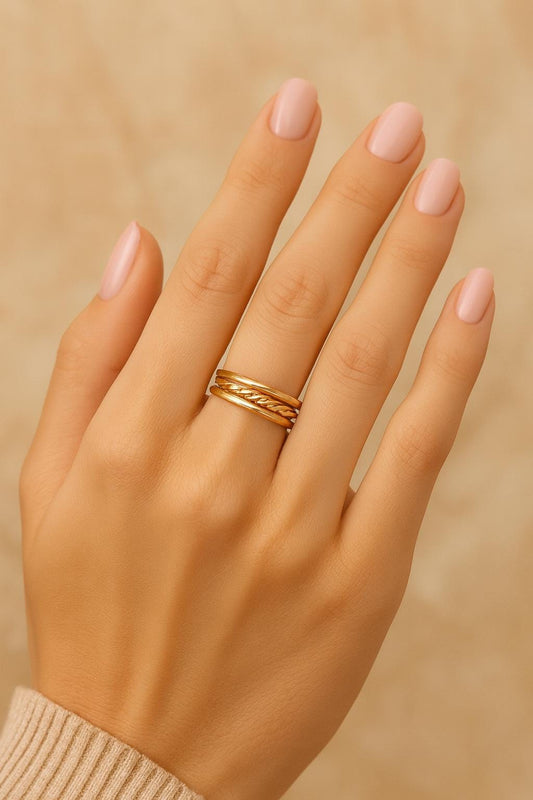 Hand wearing a gold ring on a beige background