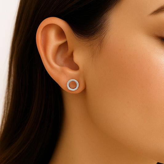 Close-up of an ear wearing a silver circle earring with a blurred background