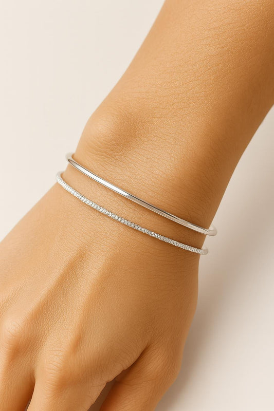 Silver bracelet on a wrist against a neutral background
