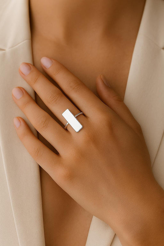 Hand wearing a silver ring with a plain background