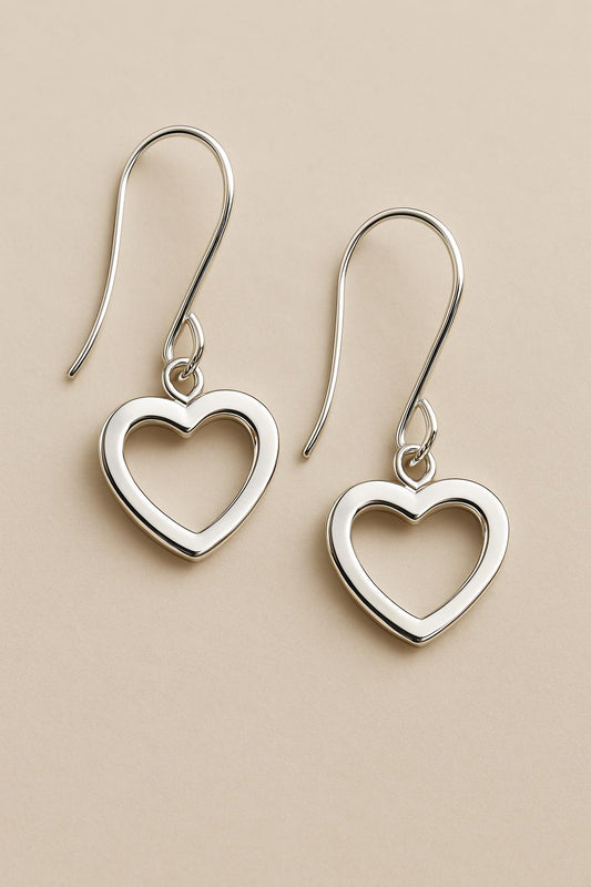 Silver heart-shaped earrings on a beige background