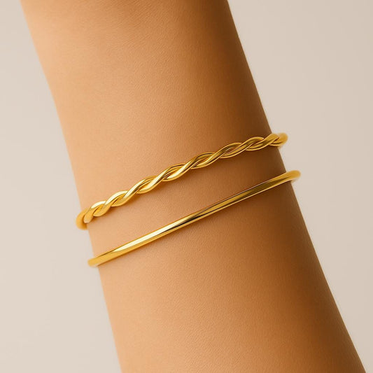 Gold braided bracelet on a wrist against a beige background