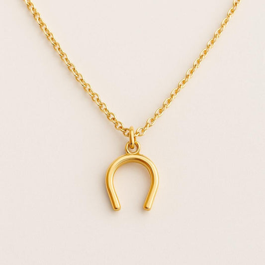 Gold horseshoe necklace on a beige background