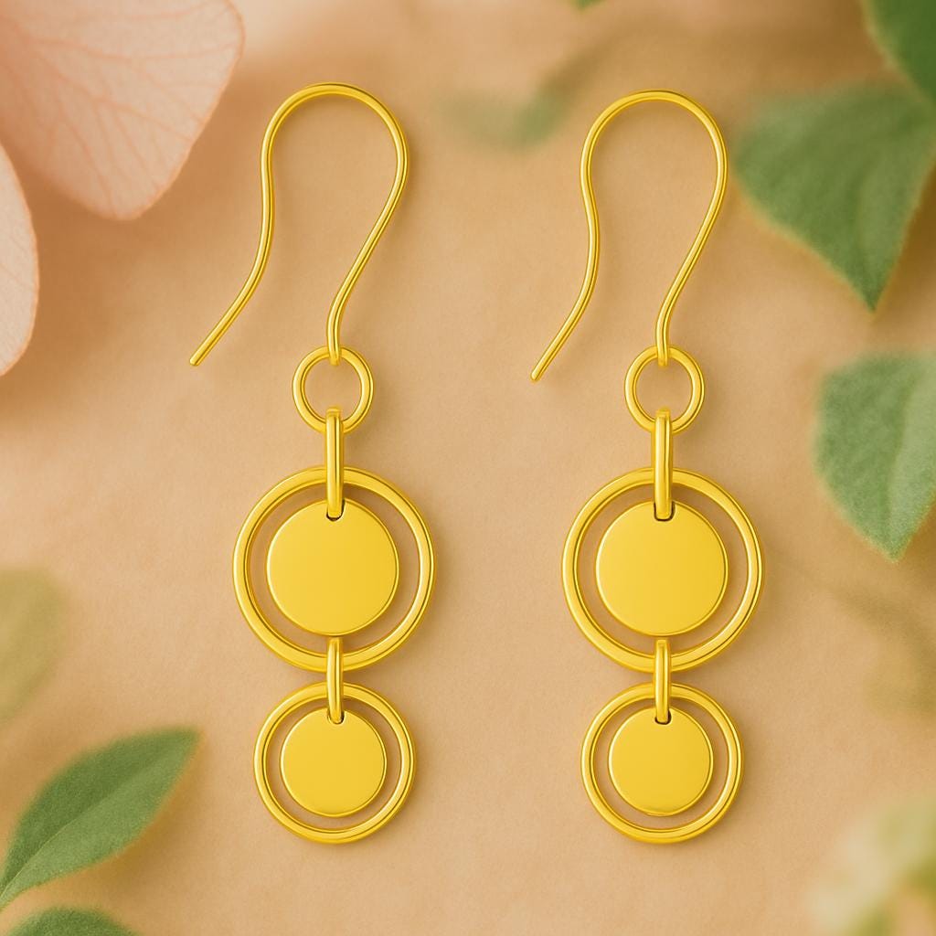 Gold earrings with circular design on a beige background with green leaves