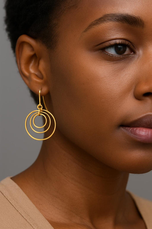Gold Brass Dangle earrings on a textured surface with a black box in the background