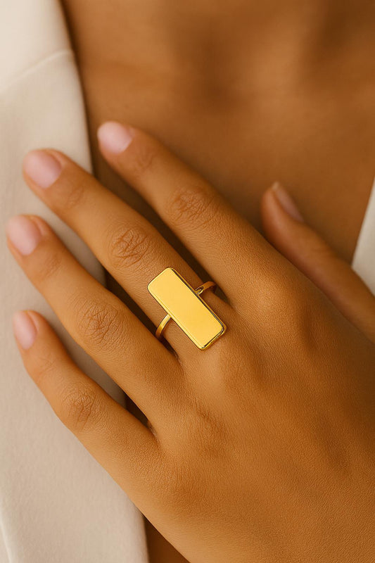Gold ring on a person's finger with a neutral background