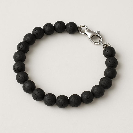 Black beaded bracelet with a silver clasp on a light gray background
