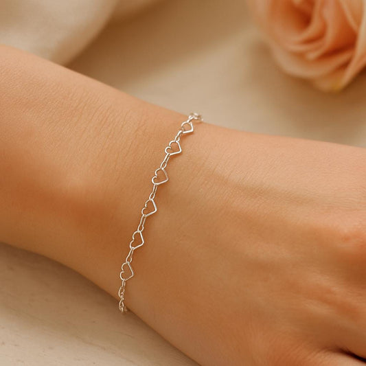 Silver heart-shaped bracelet on a wrist with a soft background