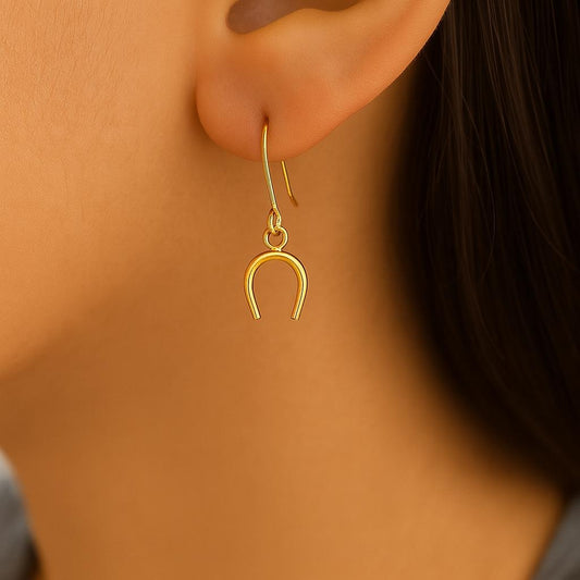 Gold horseshoe earring worn by a person with a blurred background