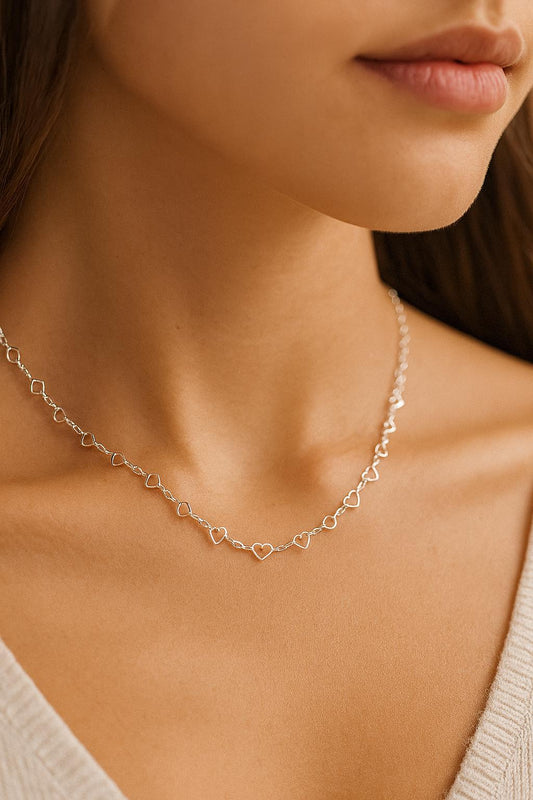 Close-up of a person wearing a delicate heart-shaped necklace.