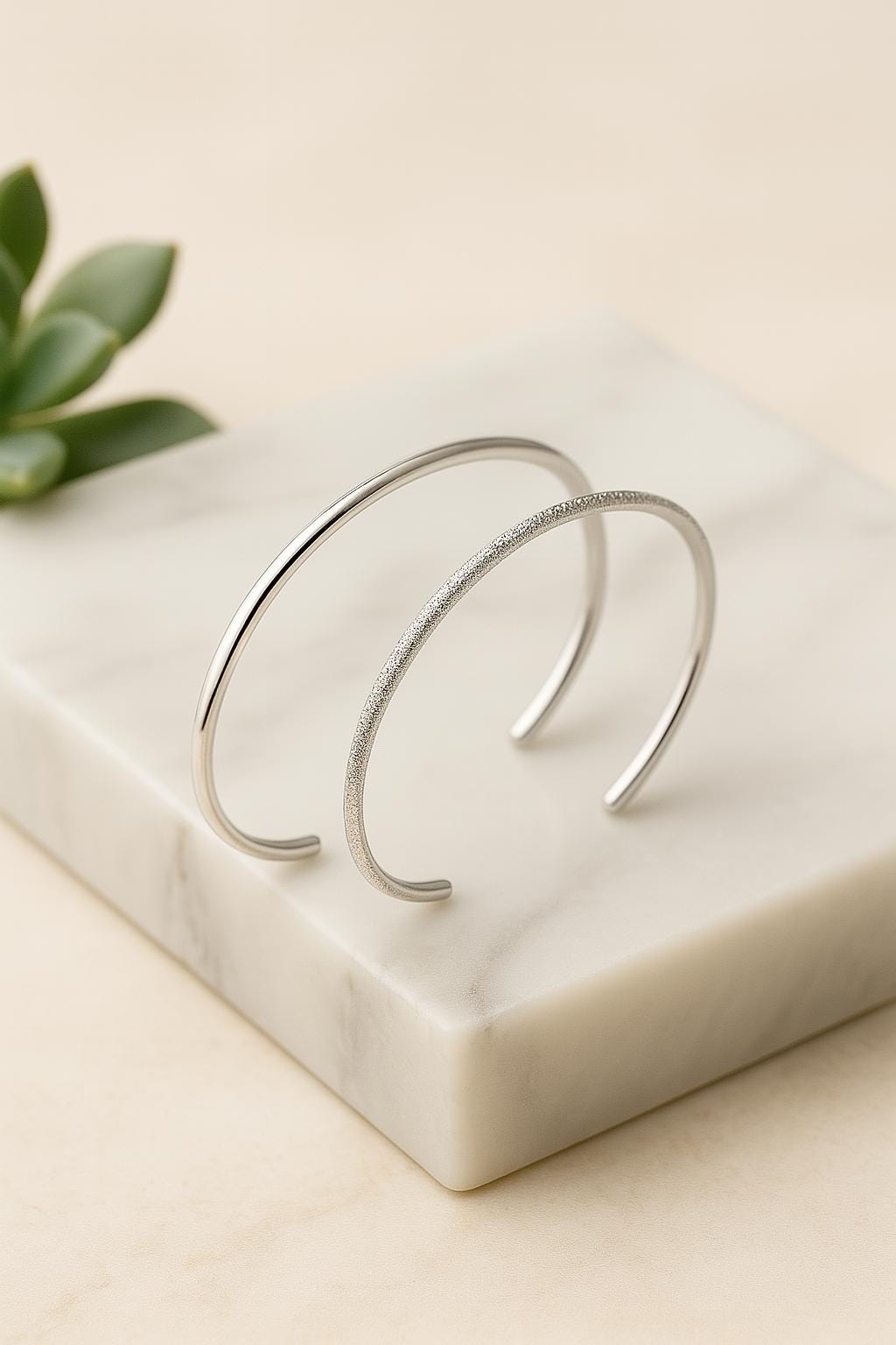 Silver bracelet on a marble surface with a plant leaf