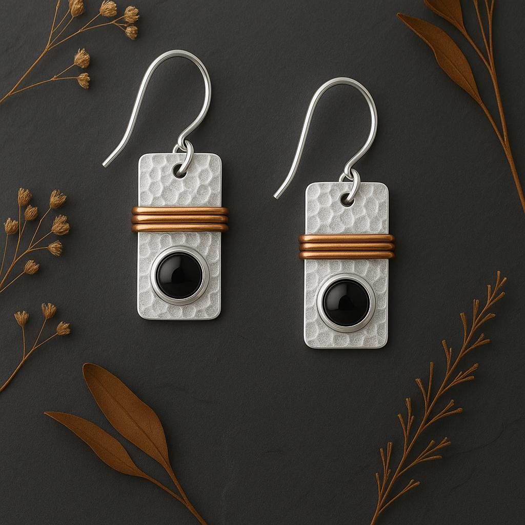 Pair of earrings with rectangular silver and gold design on a dark background with dried leaves.