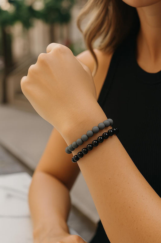 Person wearing two beaded bracelets on a blurred background