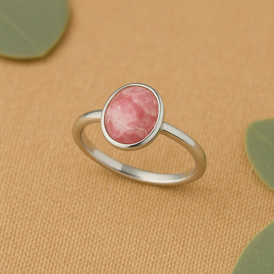 Silver ring with a pink stone on a beige background